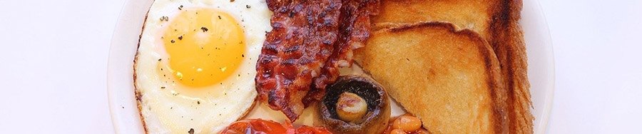 Close up of eggs, bacon, mushrooms, and fried bread.