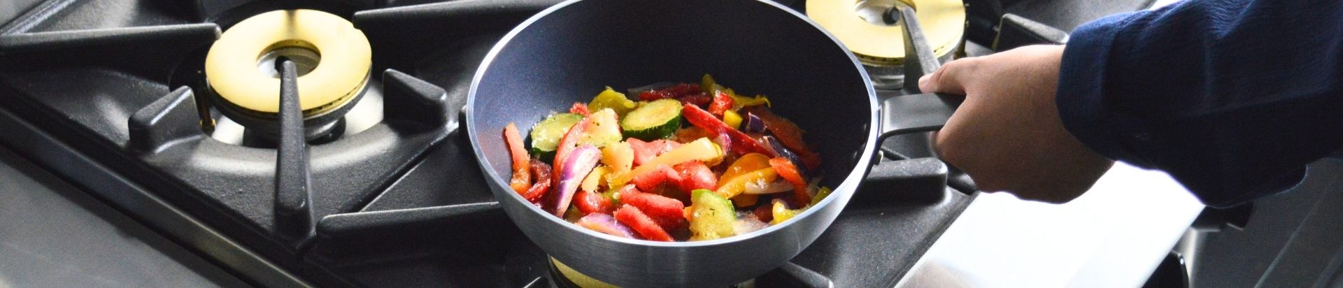 frying pan with veggies on a hob