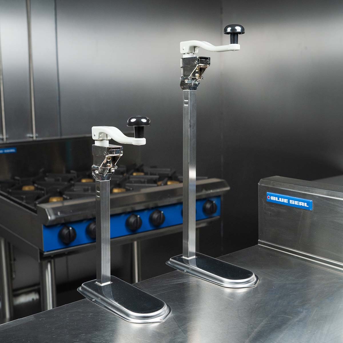 Two bench can openers securly attached to stainless steel tables