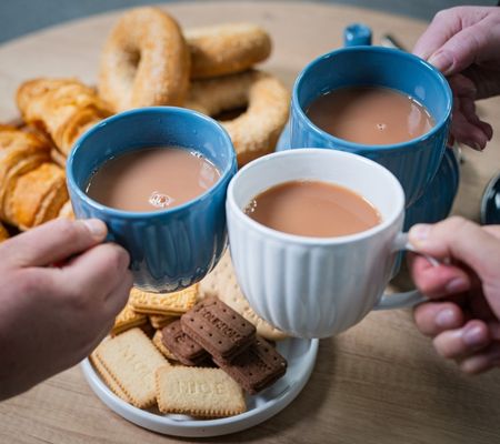 3 People clinking mugs of tea