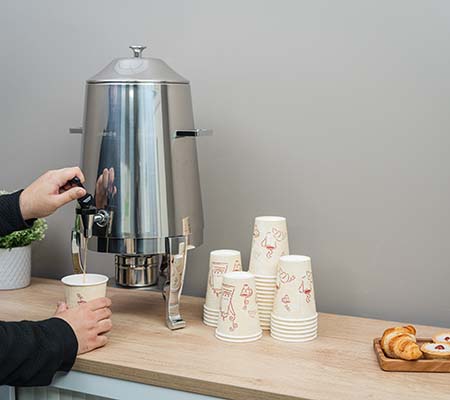 Person pouring tea from a Cooksmill Deluxe Stainless Steel Hot Beverage Tea / Coffee Urn