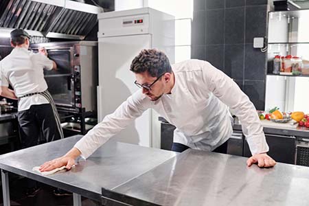 A chef cleaning a prep table