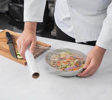 Chef putting cling film over a salad