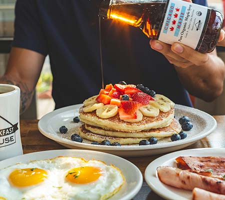 Man eating pancakes with fruit and syrup