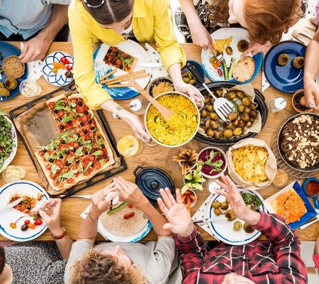 Table with lots of people round it eating