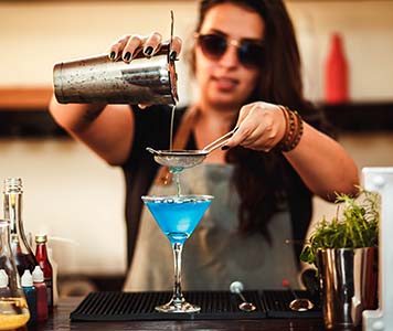 Woman pouring a cocktail from a cocktail shaker