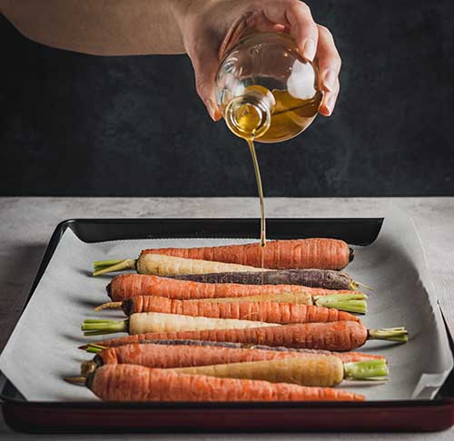 Carrots with oil being poured on them