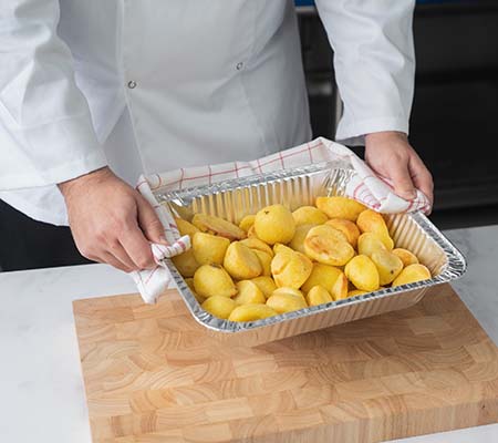 Chef with aluminium baking tray full of roast potatoes