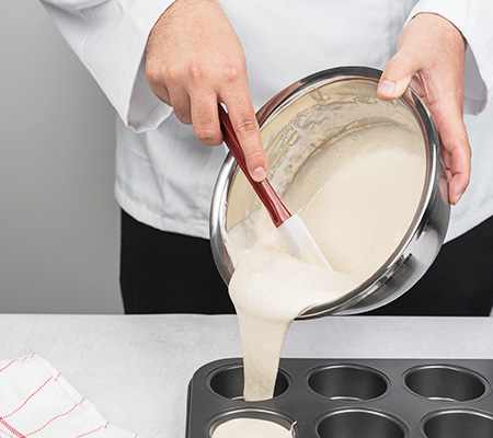 Chef using a spatula to get mixture from a bowl